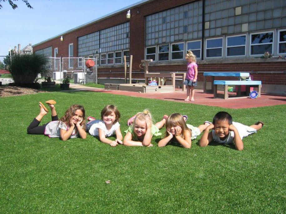 Children playing on a safe, durable playground surface featuring professional artificial turf installation by Southwest Greens at a school outdoor area.